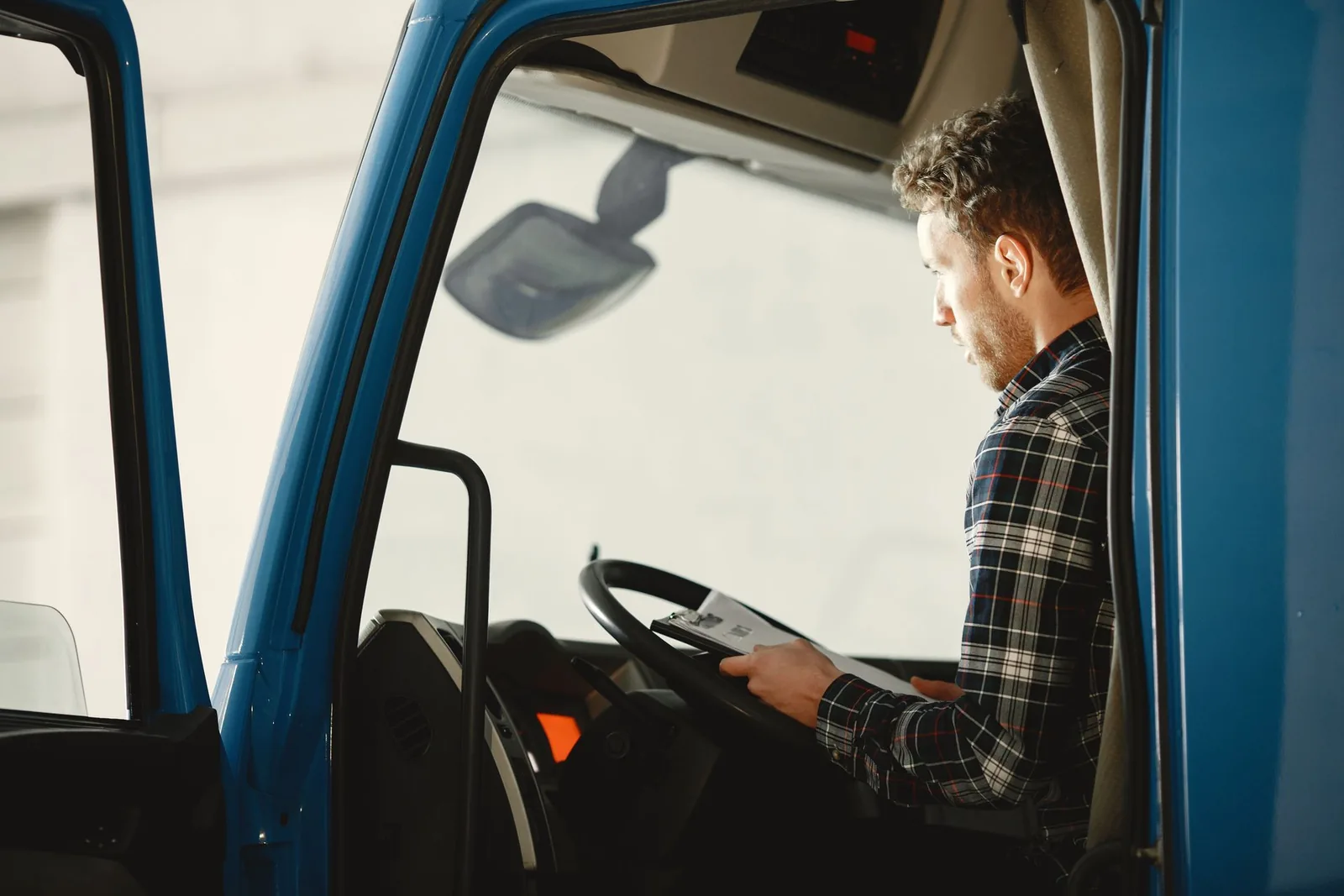 Berufskraftfahrer liest Unterlagen in der Lkw-Kabine